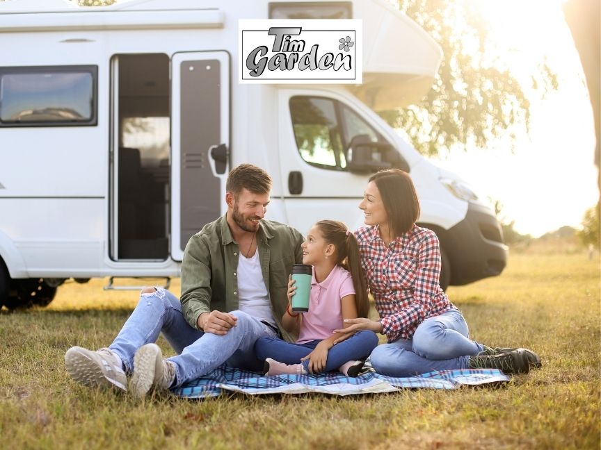 Eine Familie sitzt auf einer Decke vor Ihrem Camping Wagen